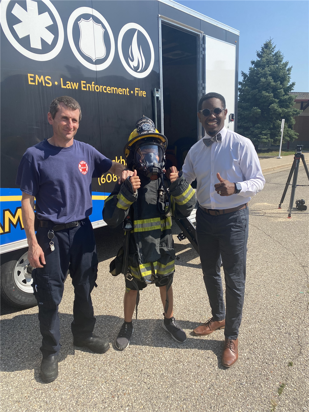  Student in firefighter gear posing for a photo with a fire fighter and the superintendent